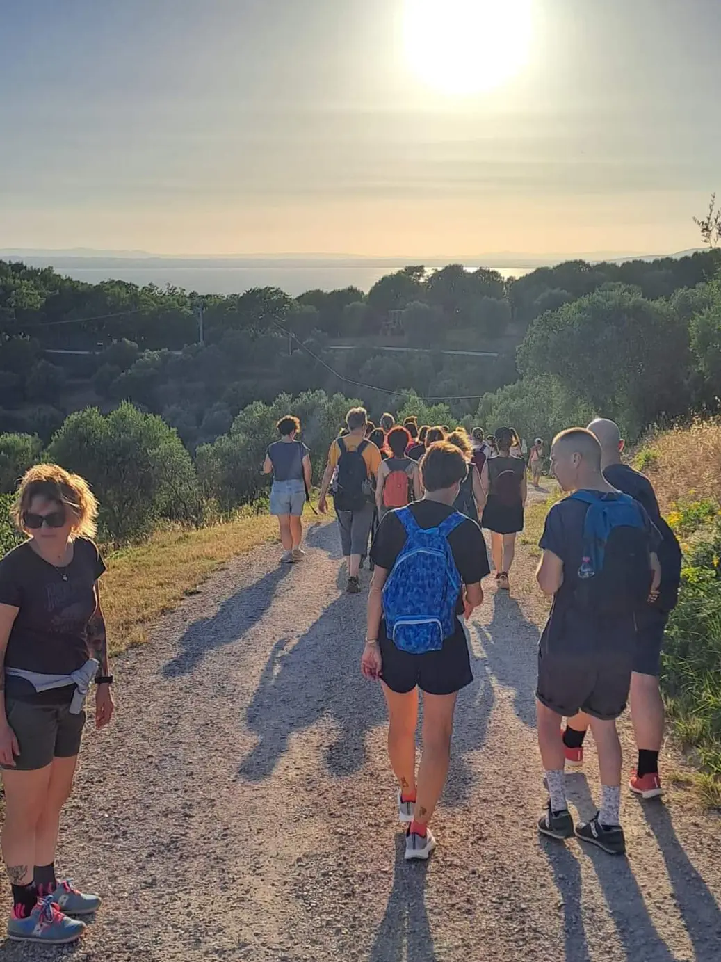 Diverse persone percorrono un sentiero durante un'escursione di trekking, sulle colline intorno al Lago Trasimeno.